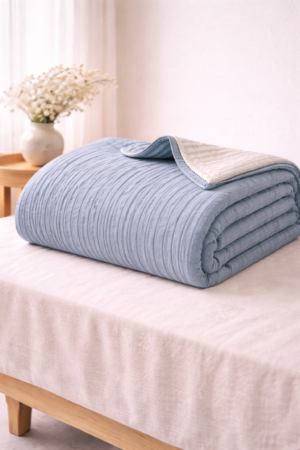 Dusty blue cotton quilt with soft stitched texture and breathable lightweight fabric in portrait style
