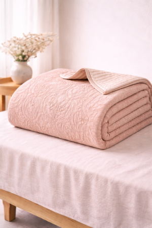 Blush pink cotton quilt with embossed paisley pattern and soft stitched detailing in portrait style